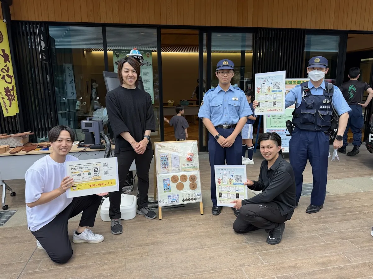 道の駅クロスウェイなかまちで、奈良西警察署の方と並んで「詐欺対策ガチャガチャ」の案内を持つ、なんでもツクールのメンバー
